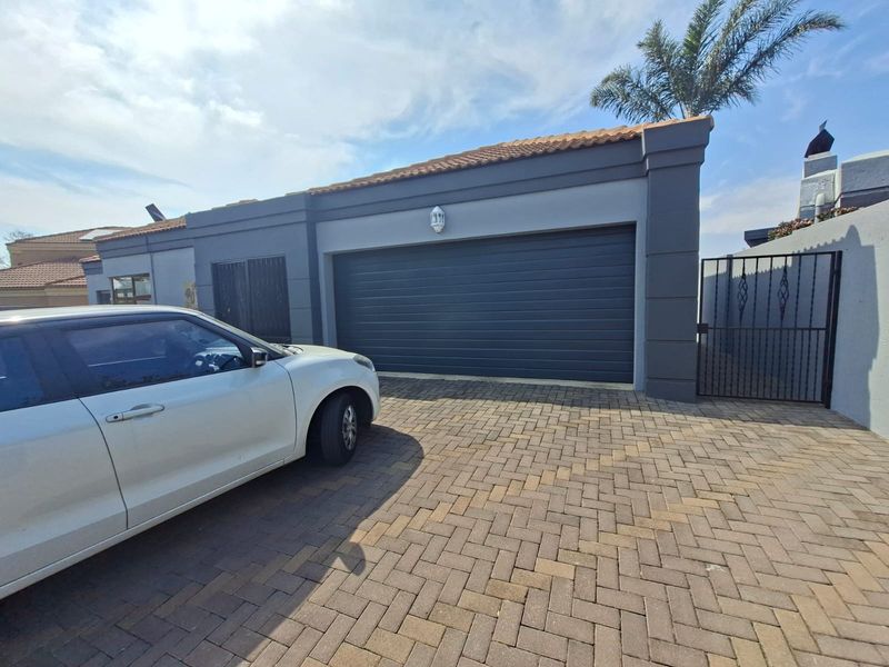 A well-maintained garage exterior featuring a modern automated door, paved driveway, and secure perimeter fencing.