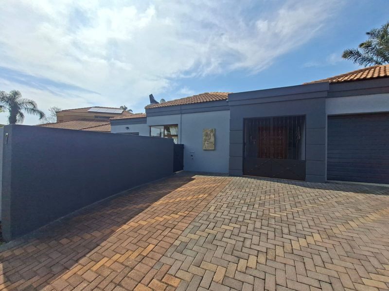 Front exterior view of the cluster property featuring a paved driveway, secure gated entrance, and modern grey facade with a tiled roof.