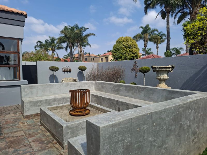 Outdoor patio area featuring built-in concrete bench seating and a central fire pit, set within a private walled garden space.