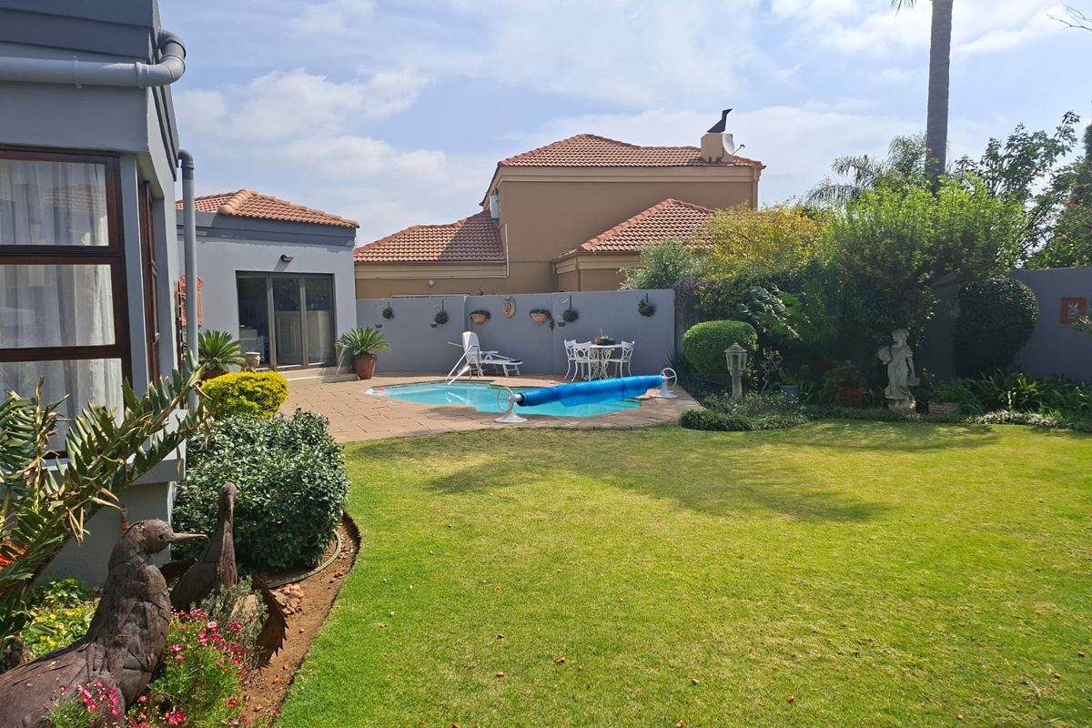 A well-maintained rear garden featuring a swimming pool, paved patio area, and established landscaping, providing a private outdoor entertainment space.
