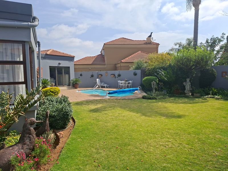 A well-maintained rear garden featuring a swimming pool, paved patio area, and established landscaping, providing a private outdoor entertainment space.