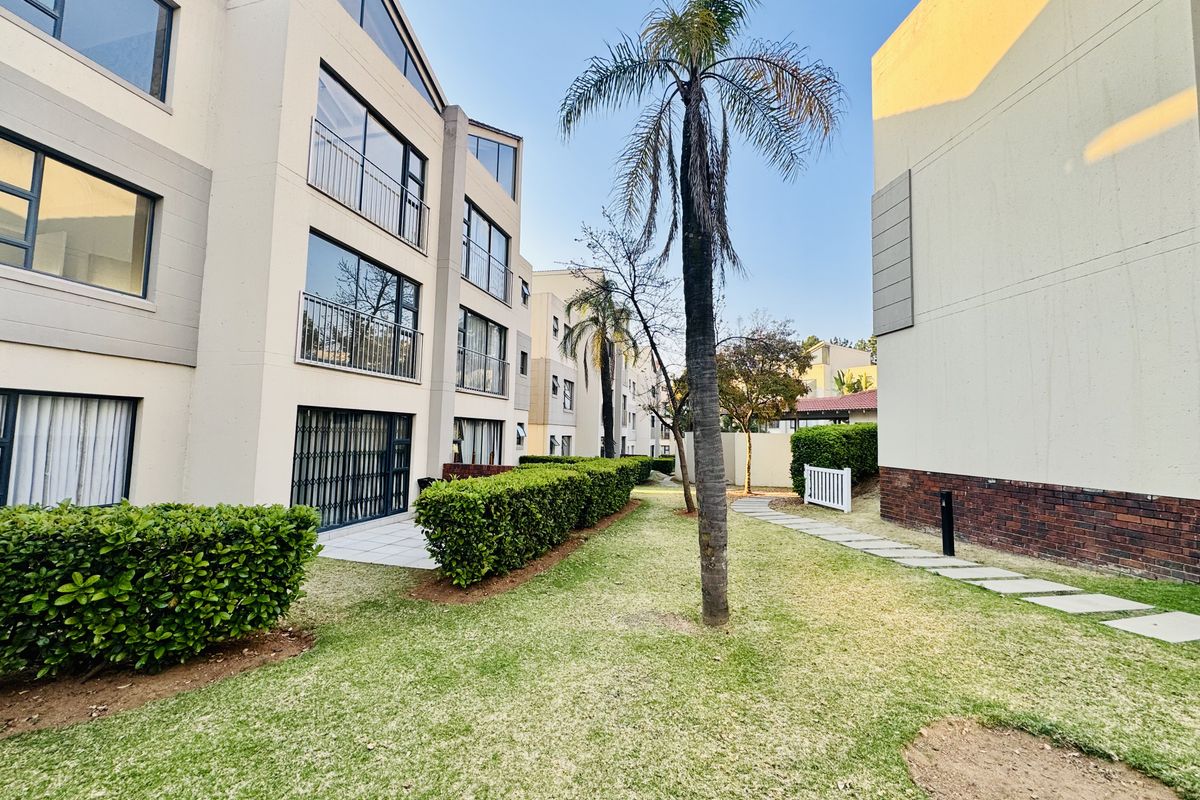A well-maintained exterior view of the apartment complex featuring landscaped gardens, paved walkways, and private balconies with security gates.