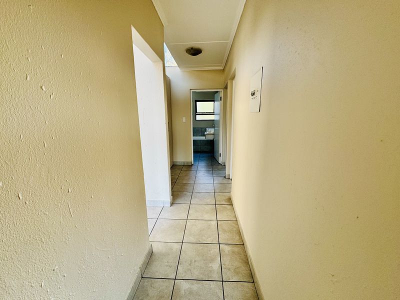 A functional hallway featuring tiled flooring and neutral wall finishes, providing access to adjacent rooms within the flat.
