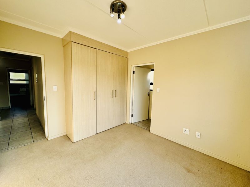A vacant bedroom featuring neutral walls, carpeted flooring, and a built-in wardrobe with light wood-finish doors.