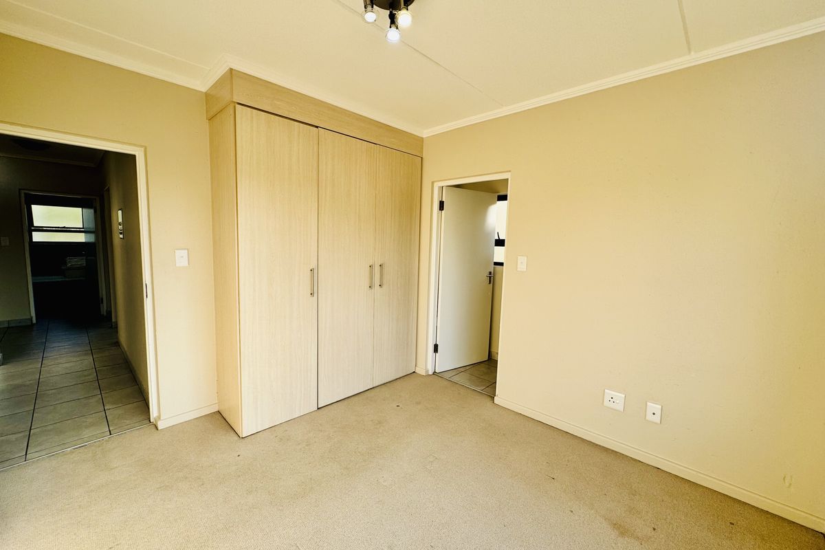 A vacant bedroom featuring neutral walls, carpeted flooring, and a built-in wardrobe with light wood-finish doors.
