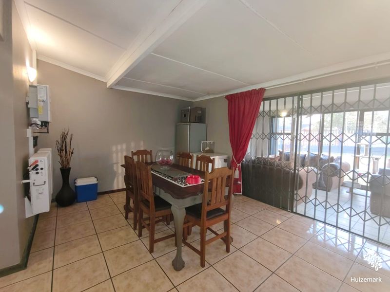 Dining area featuring tiled flooring, an exposed ceiling beam, and a sliding security gate leading to the outdoor space.
