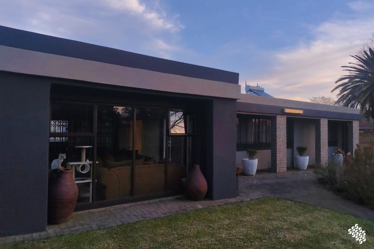 Rear exterior view of the house featuring a paved patio, sliding glass doors, and a solar water heating system on the roof.