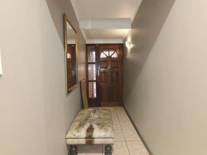 A functional entrance hallway featuring tiled flooring, a solid timber front door with glass inserts, and neutral wall finishes.