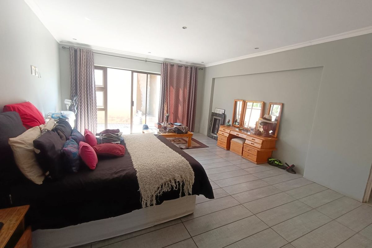 Spacious bedroom featuring neutral wall tones, tiled flooring, and a sliding glass door providing access to the exterior.