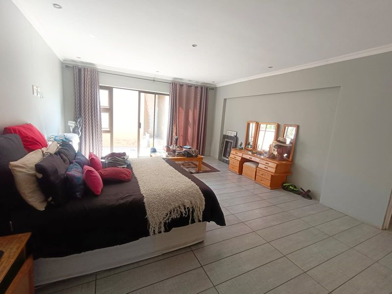 Spacious bedroom featuring neutral wall tones, tiled flooring, and a sliding glass door providing access to the exterior.