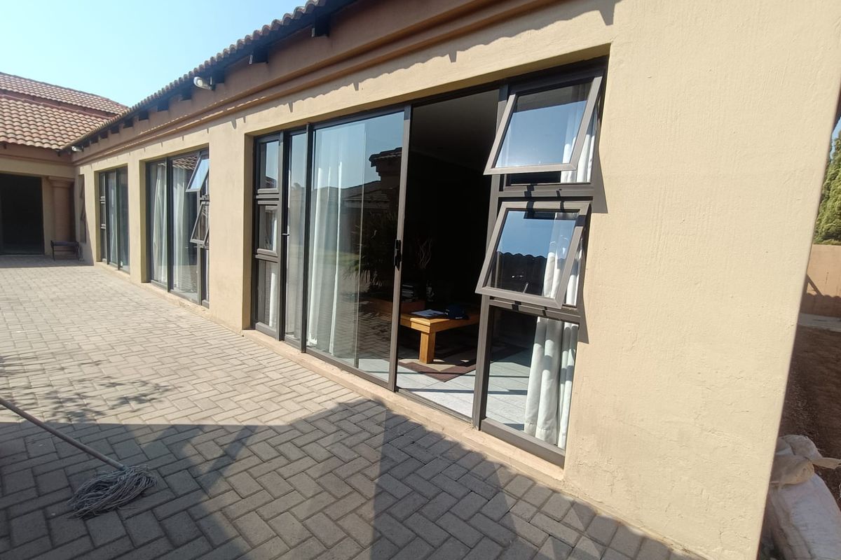 Rear view of the property featuring a paved patio area with multiple sliding glass doors and top-hung windows providing access to the interior.