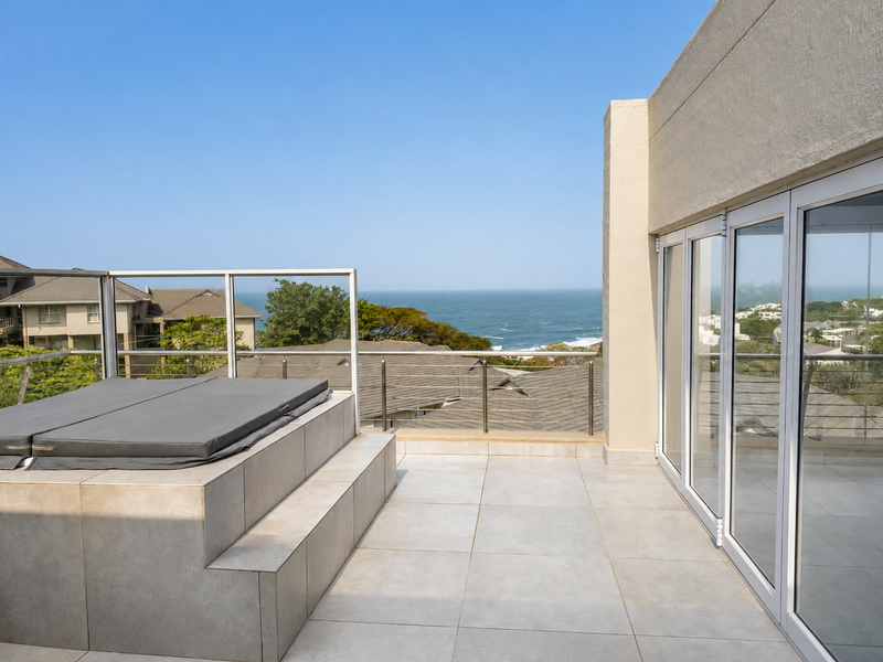 Spacious penthouse balcony featuring a built-in tiled spa, modern glass balustrades, and expansive sliding doors with panoramic ocean views.