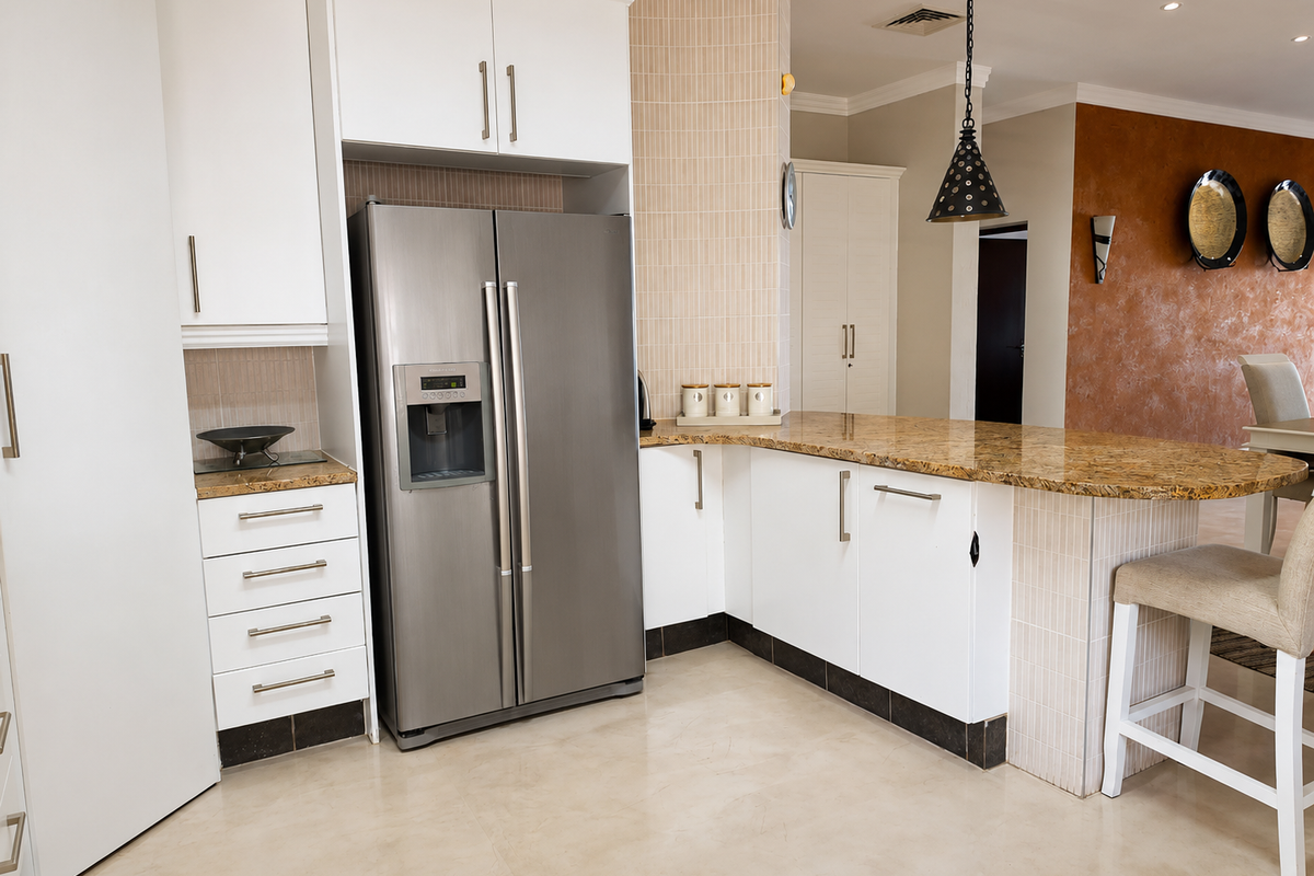Modern kitchen featuring granite countertops, white cabinetry, and a stainless steel side-by-side refrigerator with integrated lighting.