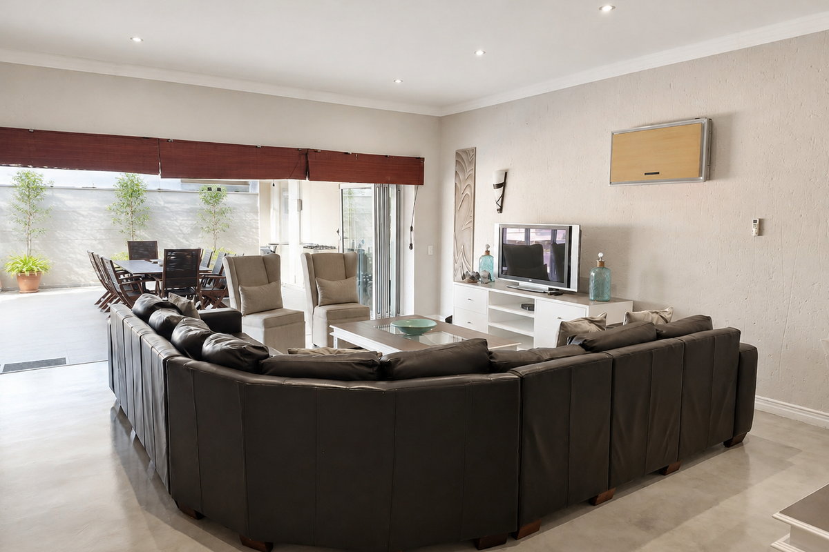 Spacious living room featuring polished concrete floors, recessed lighting, and large stacking glass doors that open onto an outdoor patio area.