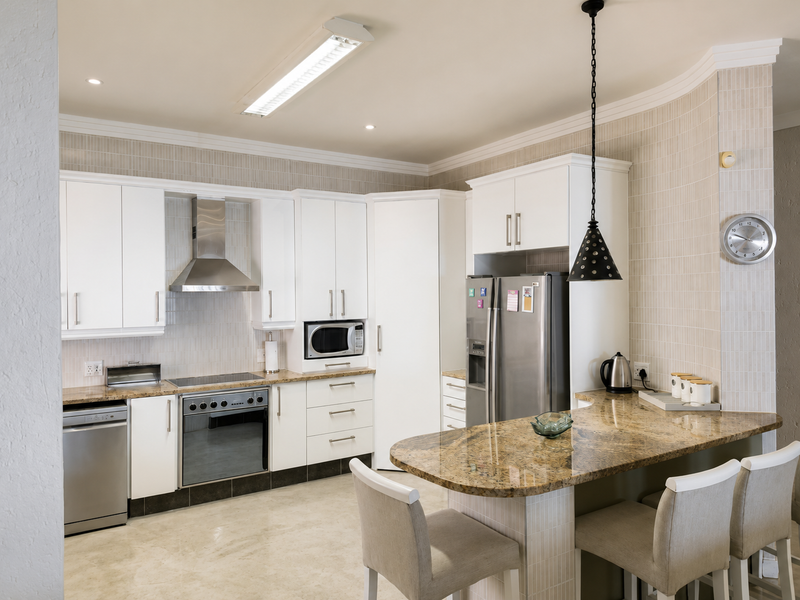 Modern kitchen featuring white cabinetry, granite countertops, stainless steel appliances, and a breakfast bar with pendant lighting.