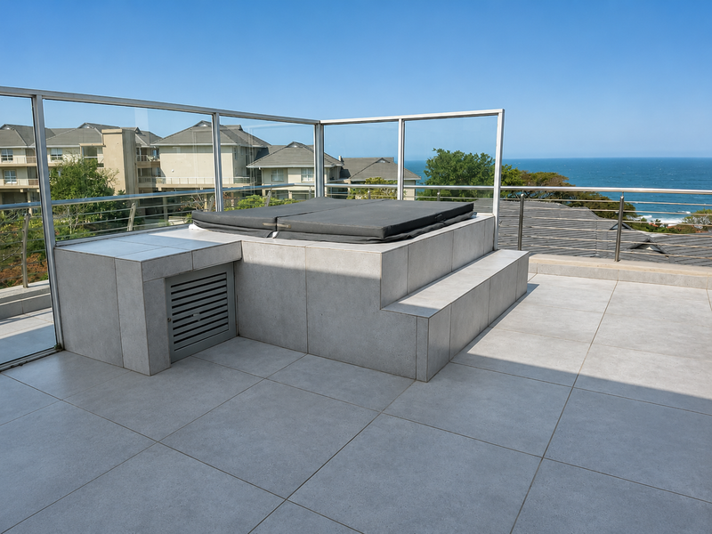Spacious penthouse balcony featuring a built-in tiled jacuzzi, glass balustrades, and panoramic ocean views.