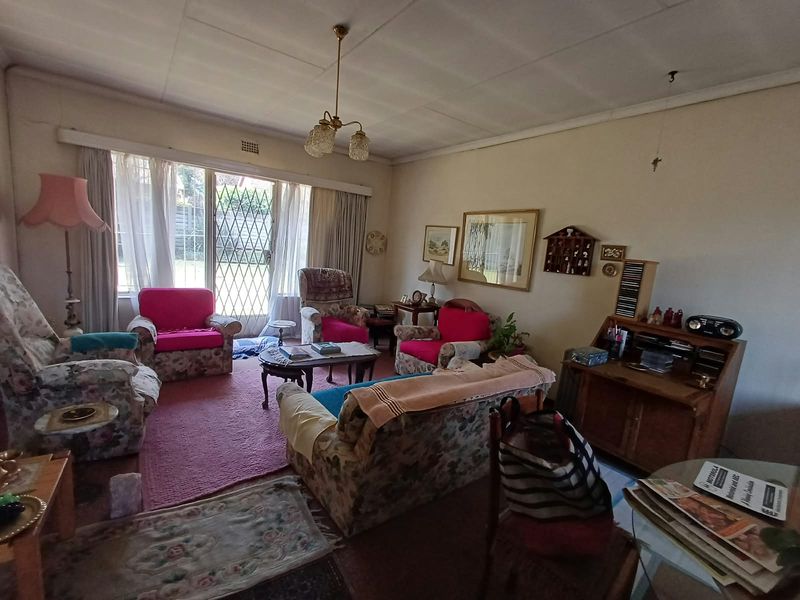 A spacious living room featuring large sliding glass doors with security gates, providing natural light and access to the exterior.