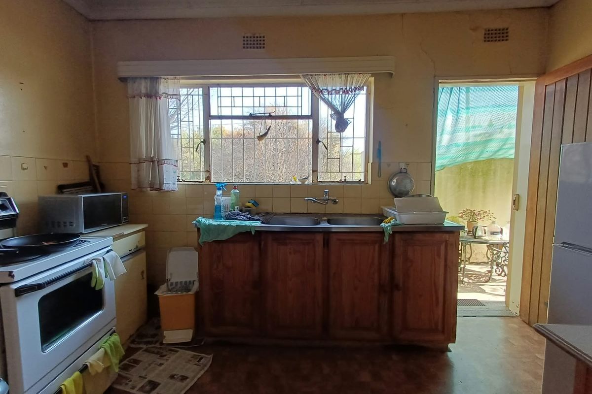 A dated kitchen featuring wooden cabinetry, a double sink, and a built-in stove, with direct access to an outdoor area.