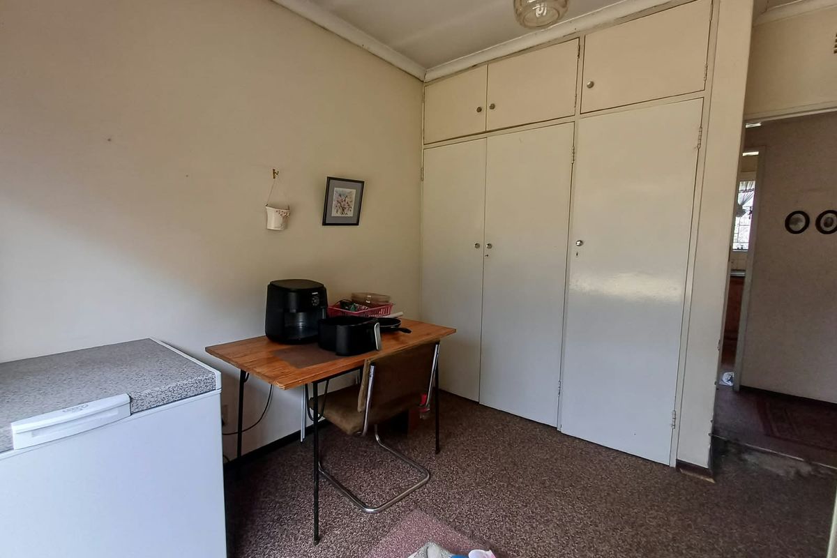A bedroom featuring built-in cupboards and carpet flooring, offering a functional space with potential for modernization.
