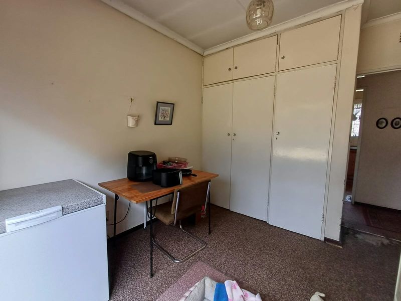 A bedroom featuring built-in cupboards and carpet flooring, offering a functional space with potential for modernization.