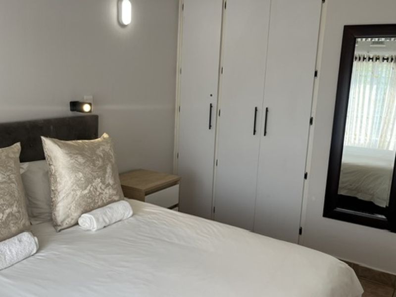 A well-maintained bedroom featuring built-in cupboards, wall-mounted lighting, and tiled flooring, offering a clean and functional living space.