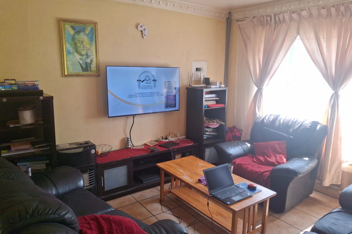 A living room featuring tiled flooring and decorative ceiling cornicing, currently used as a lounge area.