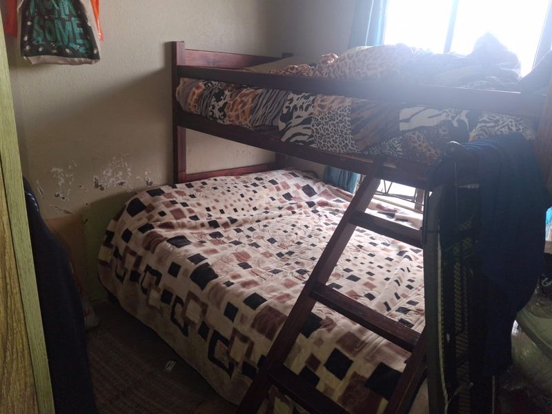 A bedroom featuring a bunk bed with visible wall surface damage and peeling paint requiring maintenance.