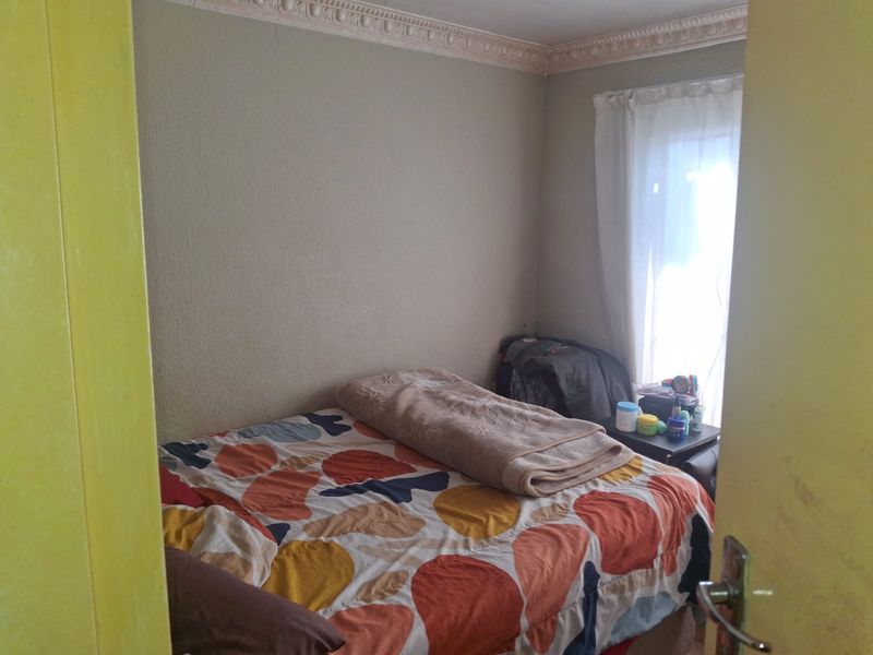 A standard bedroom featuring decorative ceiling cornicing and natural light from the window.