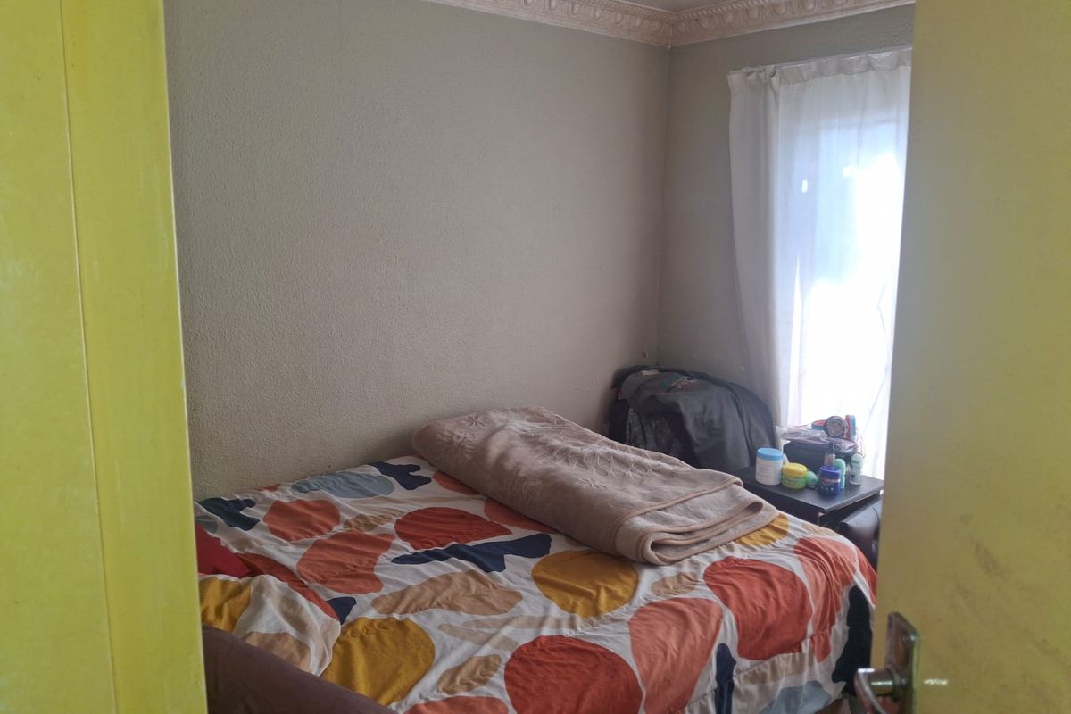 A standard bedroom featuring decorative ceiling cornicing and natural light from the window.