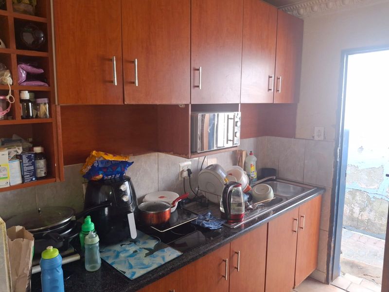 Compact kitchen featuring wood-look cabinetry, laminate countertops, and a built-in microwave, providing functional storage and preparation space.
