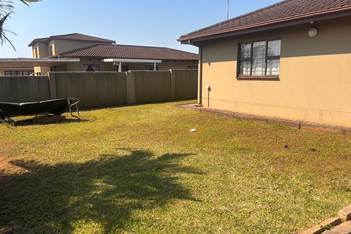 A private rear garden area featuring a lawn, perimeter walling, and a view of the townhouse exterior with a tiled roof.