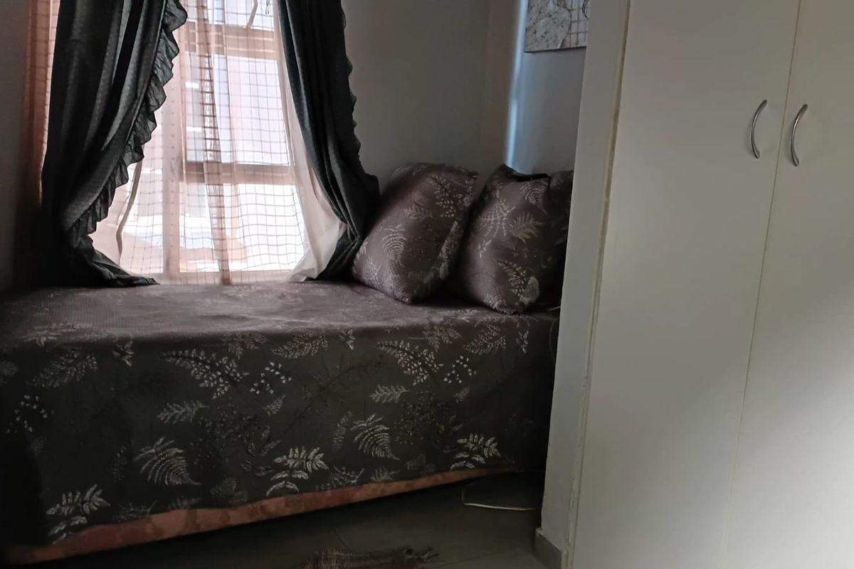 A compact bedroom featuring tiled flooring and a built-in wardrobe, providing essential storage space.
