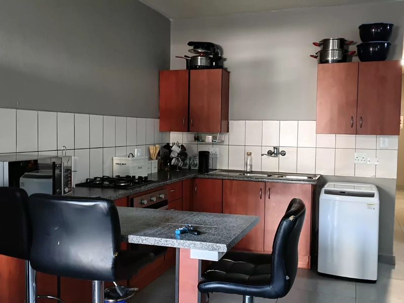 A functional kitchen featuring built-in wooden cabinetry, laminate countertops, a gas hob, and a tiled backsplash, with an integrated breakfast nook area.