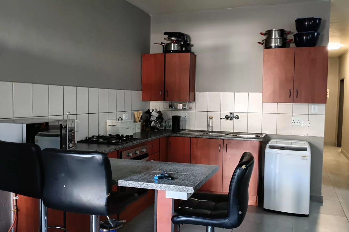 A functional kitchen featuring built-in wooden cabinetry, laminate countertops, a gas hob, and a tiled backsplash, with an integrated breakfast nook area.