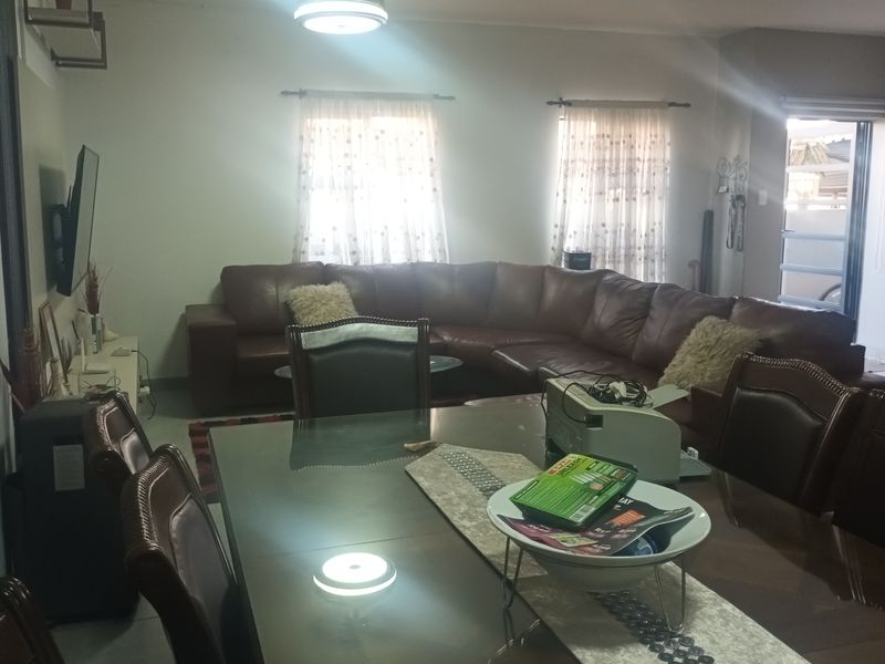 An open-plan living and dining area featuring tiled flooring and a ceiling fan, providing a functional space for relaxation and meals.