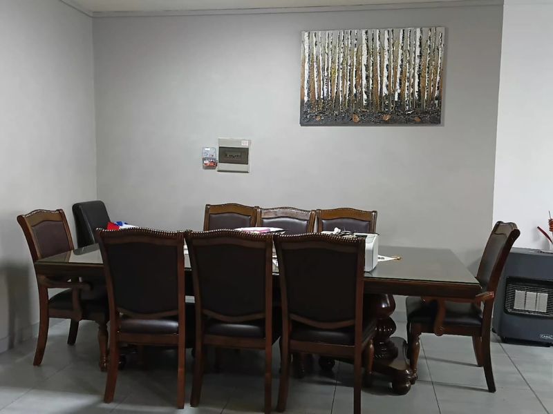 A dining room featuring tiled flooring, a wall-mounted electrical distribution board, and decorative slatted wall paneling.