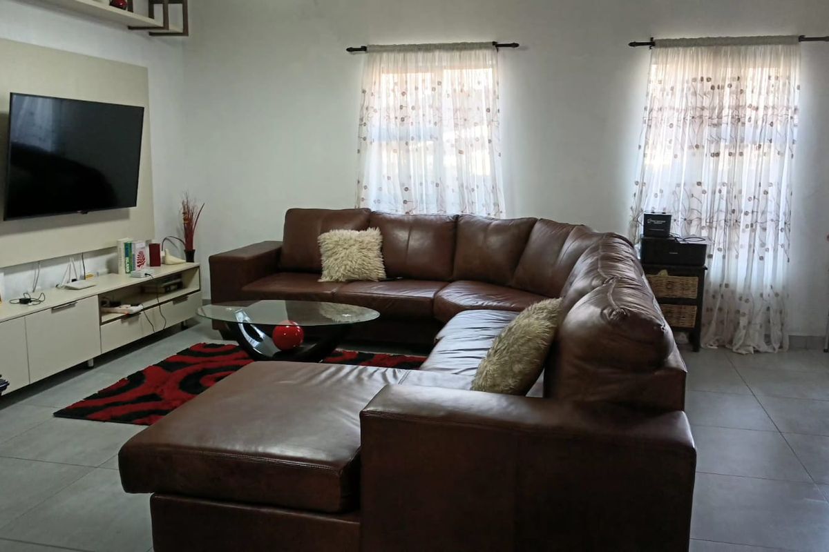 A well-maintained living room featuring neutral tiled flooring and a built-in media console unit.