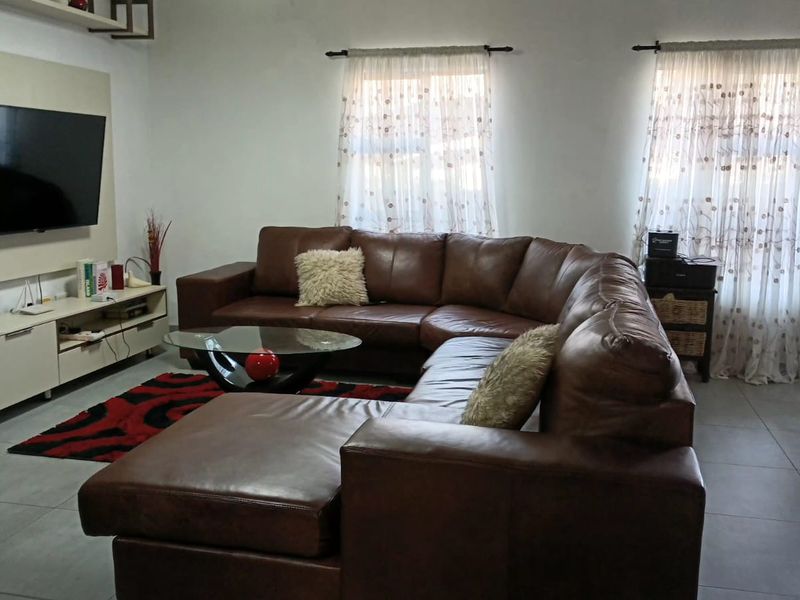 A well-maintained living room featuring neutral tiled flooring and a built-in media console unit.