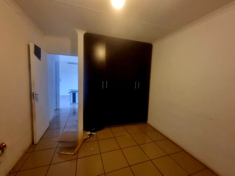 An empty bedroom featuring dark built-in cupboards, tiled flooring, and coved ceilings, offering a blank canvas for potential interior updates.
