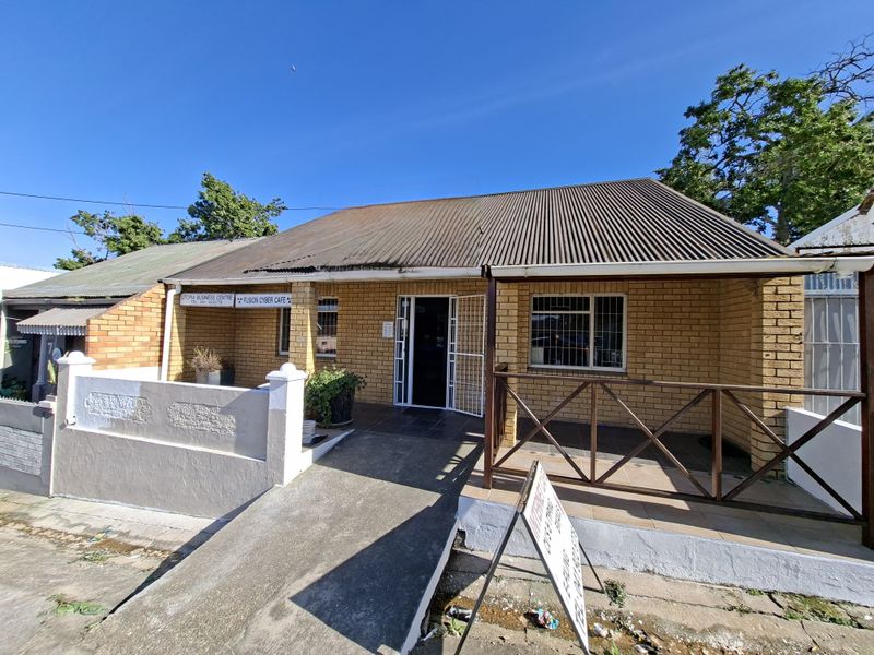 Front elevation of a facebrick townhouse featuring a corrugated metal roof, a concrete access ramp, and a covered patio area with timber balustrades.