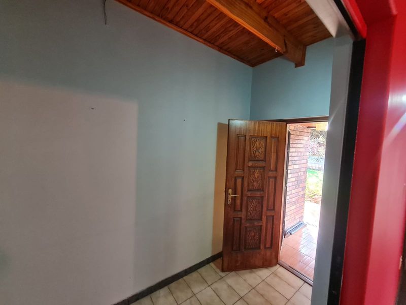An empty entrance area featuring a timber ceiling, tiled flooring, and a solid wood panel door leading to an outdoor patio.