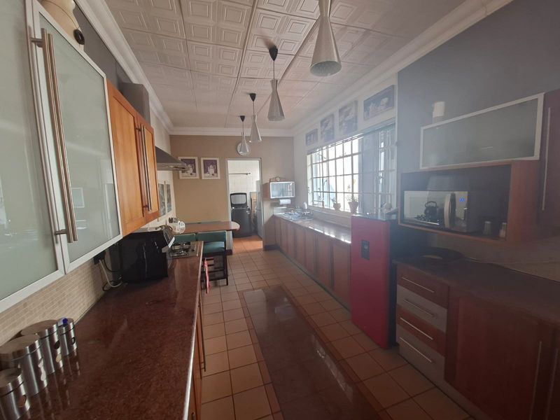 A functional kitchen featuring extensive built-in cabinetry, granite countertops, tiled flooring, and a drop ceiling, offering a practical layout for daily meal preparation.