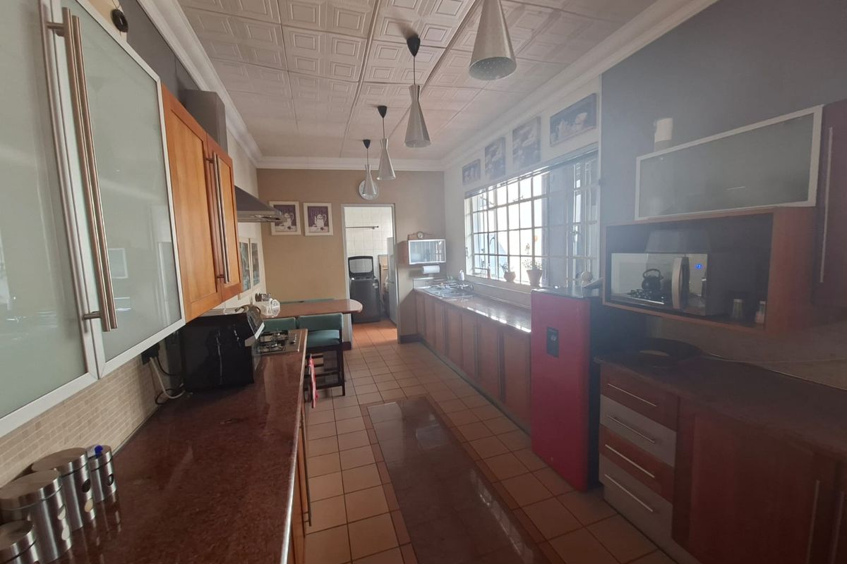 A functional kitchen featuring extensive built-in cabinetry, granite countertops, tiled flooring, and a drop ceiling, offering a practical layout for daily meal preparation.