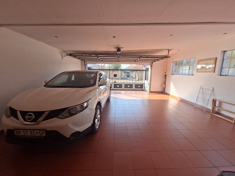 A spacious, well-maintained garage featuring tiled flooring, recessed ceiling lighting, and large steel-framed windows, providing ample space for vehicle storage.