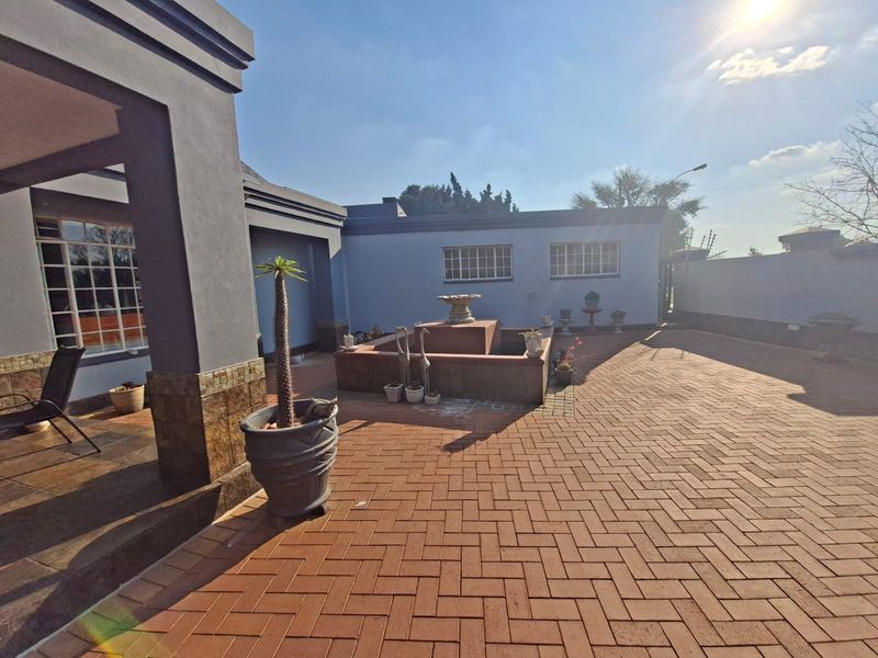 A spacious paved rear courtyard featuring a built-in water feature, covered patio area, and secure perimeter walls.