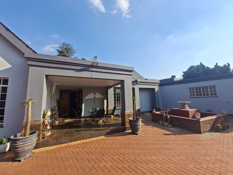 A spacious covered patio area featuring tiled flooring, overlooking a brick-paved courtyard with a built-in water feature.