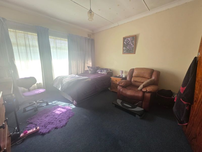 A spacious bedroom featuring large windows that provide ample natural light, finished with carpet flooring and traditional ceiling detailing.