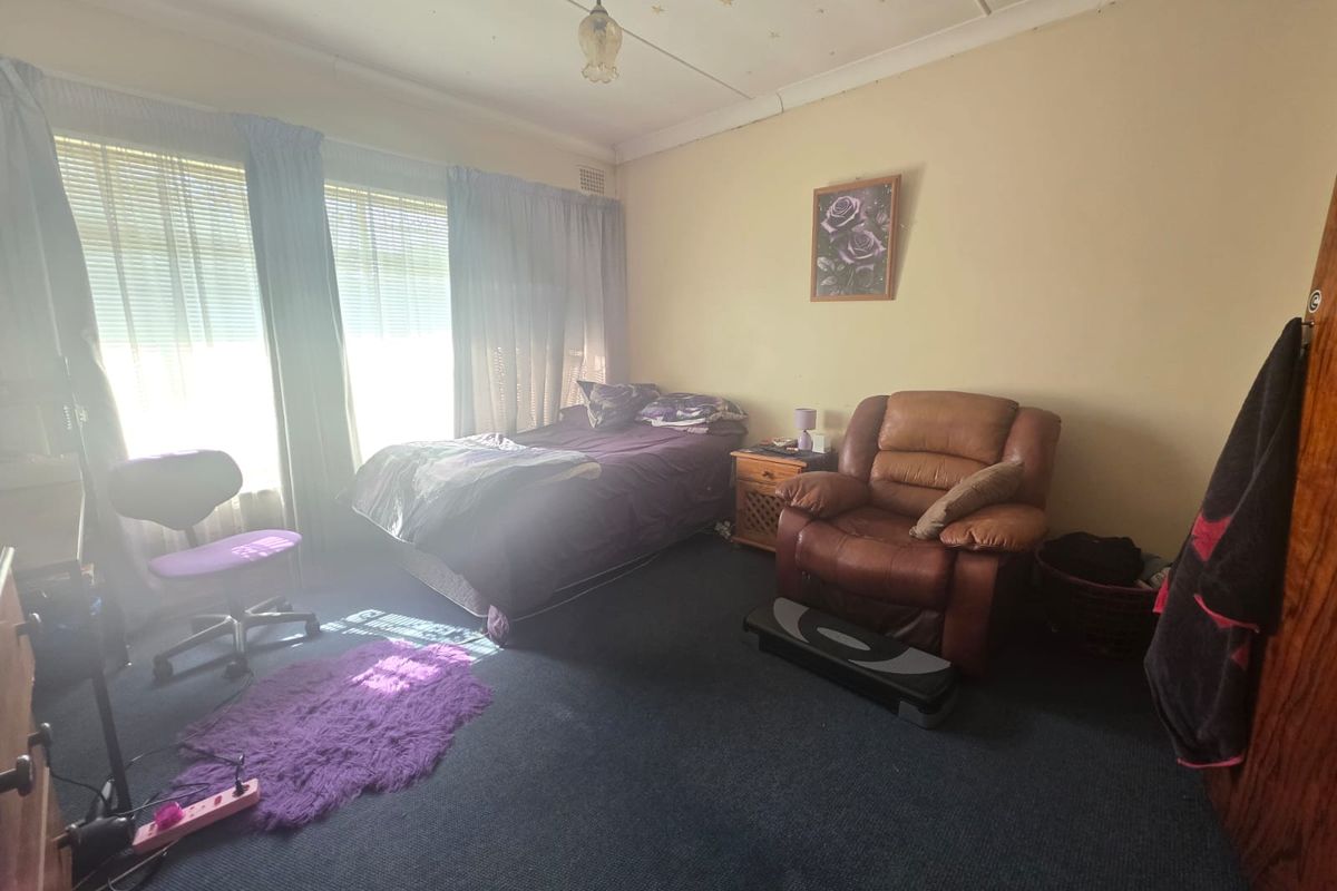 A spacious bedroom featuring large windows that provide ample natural light, finished with carpet flooring and traditional ceiling detailing.