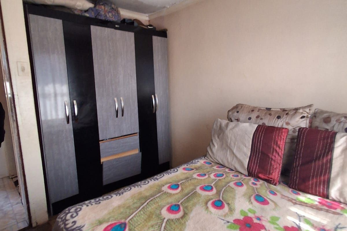 Bedroom featuring a built-in wardrobe, requiring ceiling repairs and repainting to address visible surface deterioration.