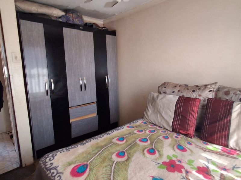 Bedroom featuring a built-in wardrobe, requiring ceiling repairs and repainting to address visible surface deterioration.